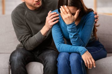 Şefkat kavramı. Adam, kederli arkadaşını teselli ediyor ve teselli ediyor. Onu kanepede otururken kucaklıyor.