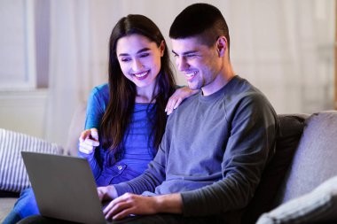 İnternetten alışveriş. Çift dizüstü bilgisayar kullanıyor, satın almayı tartışıyor ve rahat oturma odasında kanepede oturuyor.