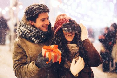 Sevgilisinin Noel Hediyesini Kutlayan Adam Gece Kentinde Işıklarla Aydınlanarak Gözünü Kapatıyor. Panorama