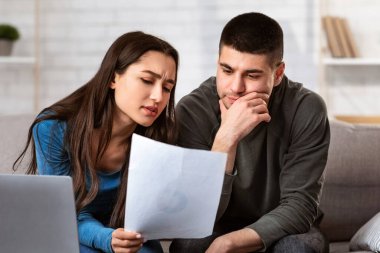 Finansal sorunlar yaşıyor. Aile bütçesini yöneten düşünceli eşler, eşinin kocasına belgeler göstermesi.