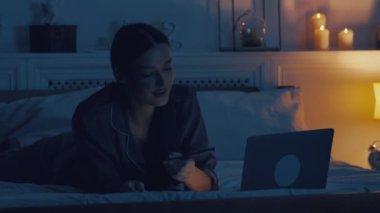 Geç ilham geldi. Kadın gazeteci dizüstü bilgisayarda geziniyor, not alıyor, geç saatlere kadar yatakta çalışıyor.