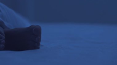 Gece uykusu. Yatakta uyuyan bir kadın, yorganın altında ayaklar