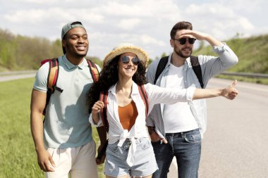 Otobanda dikilen mutlu genç, çok ırklı arkadaşlar, başparmak hareketi gösteriyorlar, araba için otostop çekiyorlar, birlikte seyahate çıkıyorlar. Bir grup milenyum öğrencisi kırsalda otostop ile seyahat ediyor.
