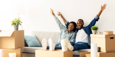 Yeni eve taşınma partisi. Karton kutular arasında koltukta oturan neşeli siyah çift ve el kaldıran genç Afrikalı Amerikalı eşler kendi evlerine taşınıp, uzaylıları kopyalıyorlar.