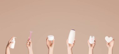 Pembe arka planda farklı vücut bakım ürünleri sunan kadın eli kolajı, boş alan. Panorama