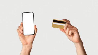 İnternetten alışveriş konsepti. Tanımlanamayan bir adam kredi kartı ve beyaz arka planda boş ekranı olan akıllı telefon kullanıyor. Tasarım için yer var. Panorama