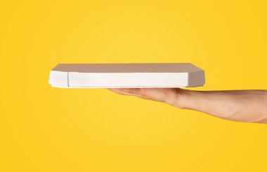 Kırpılmış erkek el görüntüsü içinde pizza olan kutu turuncu arka plan, panorama.