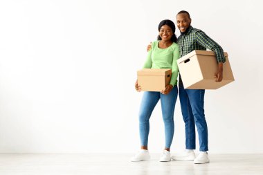 Yeni dairelerinde ellerinde karton kutularla duran mutlu siyah çiftin tam uzunlukta portresi, kendi dairelerine taşındıktan sonra neşe dolu Afrikalı Amerikalı eşler,