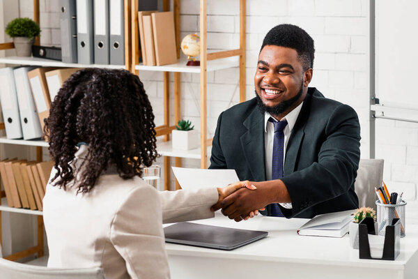 Счастливый менеджер по персоналу и молодой кандидат на работу пожимает руку в современном офисе компании
