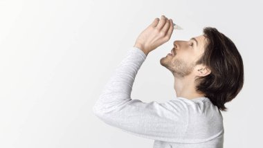 Gözlerinde kuru ve acı var. Göz damlası damlayan adam, profil