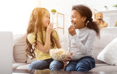 Komik karikatür izlerken ve evde koltukta oturan patlamış mısır yemek arkadaşlarım