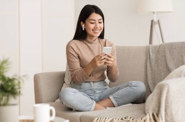 Öğrenci Kız Kanepede dinleniyor, Müzik dinliyor ve telefonda sohbet ediyor