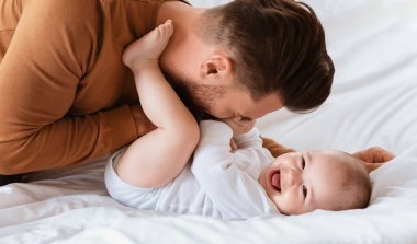 Baba sevgisi. Baba, küçük oğlana sarılıp evde yatarak vakit geçiriyordu. Babacığının şirin bebekle oynamasına bayılıyorum. Babalık, Ebeveynlik, Neşe ve Çocuk Bakımı
