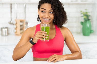 Bağışıklık sistemini güçlendir. Spor sutyenli, ev yapımı meyve suyu içen, fotokopi odasına bakan afro kadın portresi.