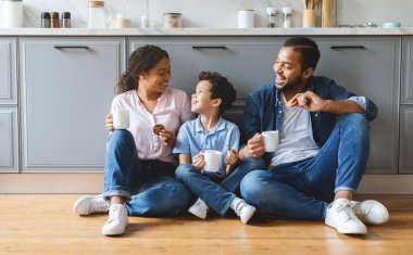 Neşeli bir aile mutfakta birlikte kaliteli zaman geçirir. Aileler oğullarıyla kahkahalarını paylaşırken sıcak bir evde atıştırmalık ve içeceklerin tadını çıkarıyorlar..
