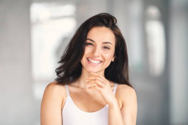 Genç beyaz bir kadın ev banyosunda kendini şımartıyor. Parlak bir şekilde gülümsüyor, güzelliğini sergiliyor ve bir anlık rahatlama ve kendine dikkat etme anını kucaklıyor..