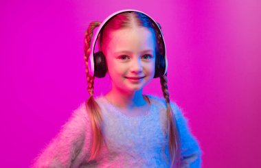 A cheerful preteen girl poses confidently with her hands on her hips, showcasing her stylish braids and cozy sweater. She listens to music through large headphones in a vibrant, neon-lit space. clipart