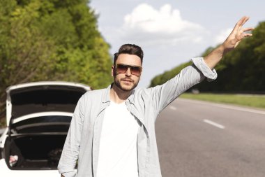 Genç beyaz adam arabadan el sallamaya çalışıyor, yardım istiyor, arkadaşları bozuk aracı tamir etmeye çalışıyor, yolda lastiği patlamış. Milenyum adamı otostop çekiyor, acil yardıma ihtiyacı var.