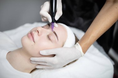 Güzellik salonunda, bir kadın kalıcı makyaj prosedürünü şımartır. Yetenekli bir profesyonel, uzun süreli sonuçlar için makyaj yapar, rahatlama ve tatmin sağlar..