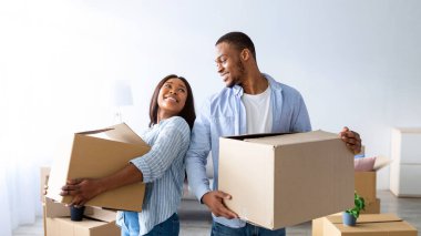 Ev taşıma konsepti. Afro-Amerikan çifti yeni evlerinde kutu taşıyorlar, fotokopi alanı. Eşyaları olan genç kiracılar yeni bir eve taşınıyor.