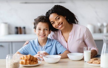 Bir anne ve oğlu sıcak mutfaklarında kahvaltı ederken keyifli bir an. Etrafları yemek ve içeceklerle dolu kâseler ve bardaklarla çevriliyken gülümserler. Aşkı ve birlikteliği temsil ederler..