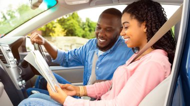 Seyahat kavramının tadını çıkarıyorum. Afro-Amerikalı gülümseyen bir çiftin el ele tutuşup haritaya bakması lüks arabaların içinde oturmaları, yolculuk için en iyi yolu seçmeleri, tatile çıkmaları.