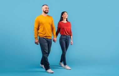 Evli bir çift el ele yürür, sevgi ve sevgi saçar. Günlük giysiler içinde, gülücüklerini ve sıcaklıklarını paylaşıyorlar, parlak mavi bir arka plana karşı, bağlarını yansıtıyor, kopyalama alanını.