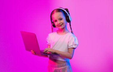 A trendy preteen girl stands alone in a vibrant neon-lit environment, engaging with her laptop while wearing headphones, immersed in her digital world and modern lifestyle. clipart