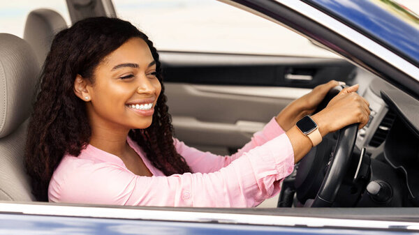 Профиль профиля портрет радостной афроамериканки за рулем автомобиля, идущей на работу или в путешествие во время летних каникул. Счастливая дама едет на новеньком хорошем автомобиле, делая тест-драйв в дилерском салоне