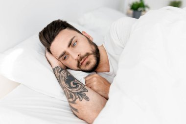 Bin yıllık üzgün adam yatakta tek başına uzanıyor, yalnızlıktan acı çekiyor ve sorunları düşünüyor, kopya uzayı. Erkek stresi ve depresyonu, uykusuzluk ve ilgisizlik..