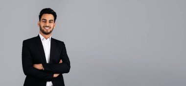 A Middle Eastern businessman stands confidently in a studio, wearing a sleek suit and smiling. He embodies success and modern entrepreneurship, showcasing a dynamic corporate lifestyle, copy space clipart