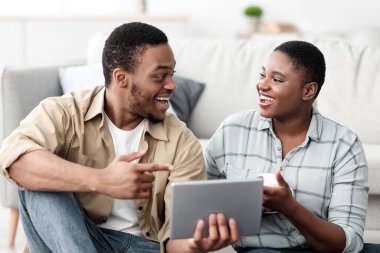 Neşeli Afro-Amerikan Turist Ailesi Tablet Rezervasyon Biletlerini Evlerinde Bavullarıyla Oturarak İnternetten alıyor. Bilgisayar Konsepti için Seyahat Uygulaması. Seçici Odaklanma