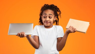 Books vs Gadgets Konsepti. Kafası karışmış Afro-Amerikalı kızın dijital tablet ve kağıt el kitabı tutarken portresi, karşılaştırma, belirsiz ergen seçimi. Modern Eğitim, Gençlik ve Öğrenme