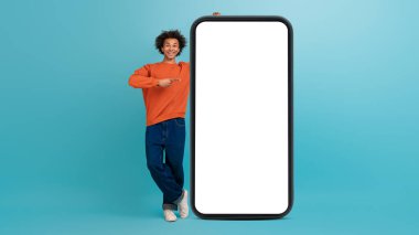 Kıvırcık saçlı genç bir Afro-Amerikalı büyük boş bir akıllı telefon ekranının yanında duruyor..