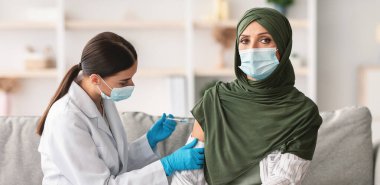 Aşılama. Üst düzey Müslüman Kadın Hasta, Covid-19 'a karşı aşı oluyor, hemşire içeride şırınga enjekte ediyor. Salgın sırasında Coronavirus Antiviral Bağışıklık Kampanyası