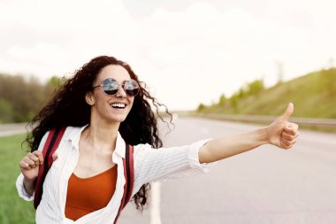 Neşeli genç bir bayan otobanda araba sürüyor, otostop çekiyor, boş bir alanda otostop çekiyor. Güzel bir milenyum dişisi yaz macerasına çıkıyor, otostop yapıyor.
