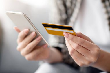 Modern cep telefonu ve kredi kartı tutan, evde otururken mal ve hizmetleri ödeyen, internet üzerinden alışveriş için mobil uygulama kullanan, kapalı çekim yapan bir kadın. E-ticaret, online bankacılık