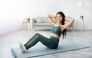 Atletik Hintli kadın yoga minderi üzerinde egzersiz yapıyor, evde karın kaslarını güçlendiriyor. Çekici Doğulu kadın formda ve sağlıklıymış. Yurtiçi spor konsepti