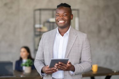 Takım elbiseli siyahi bir adam, bir grup profesyonel üzerinde bir ofis toplantısında işbirlikçi tartışmalara giriyor. Bir proje üzerinde çalışırken fikirleri ve stratejileri araştırıyorlar..