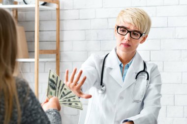 Bedava ilaç. Ofisteki kadın doktor hastanın parasını reddediyor.