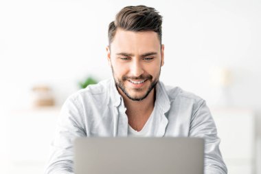 Merkez ofis konsepti. Bilgisayarda çalışan mutlu adamın yakın plan portresi, iç mekandaki iş yerinde oturuyor. Heyecanlı erkek öğrenci bilgisayar, öğrenim ve eğitim kullanıyor