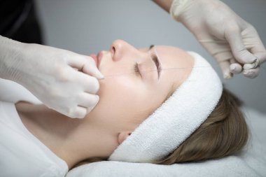 Bir kadın kalıcı bir makyaj işlemi sırasında bir kuaförde dinlenir. Yetenekli eller, yüz hatlarını geliştirmek için kusursuz teknikler uyguluyor. Şımarık bir deneyim sağlıyor..