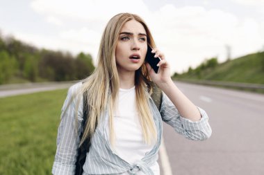 Kafası karışmış genç sarışın bir kadın, kendini kaybolmuş hissediyor, cep telefonundan arıyor, yardım istiyor, boş yer arıyor. Stresli milenyum dişileri otostop çekerken araba yakalayamaz.