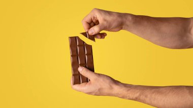 Çikolata kıran adamın yakın plan görüntüsü, turuncu arka plan. Uzayı kopyala Panorama