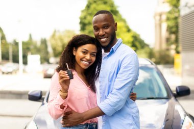 Luxuy otomobilinin anahtarlarını gösteren mutlu siyah kadın, karısını kucaklayan koca, araba kiralama servisini kullanan genç aile, galeriden yeni araba alan çift, gülümseyen ve kameraya bakan kadın.