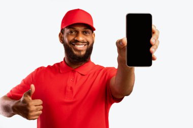 Teslimat Başvurusu. Afrika Kuryesi Cep Telefonu Gösteren Boş Ekran Hareketi Başparmak Tavsiyesi Ekspres Nakliye Uygulaması Sarı Arkaplan 'da. Stüdyo Çekimi