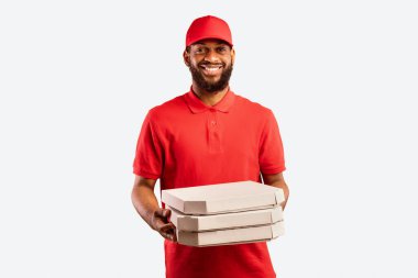 Pizza teslimatı. Siyah Pizzacı Kurye Pizza Holding kutularını teslim ediyor Sarı Stüdyo Arkaplan 'da duruyor.