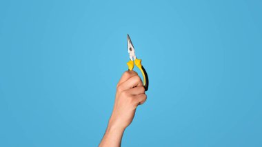 Mavi arka planda düz pense tutan tamirci görüntüsü, yakın plan. Panorama