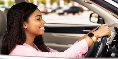 Kendine güvenen profesyonel sürücü. Sürücü koltuğunda oturan mutlu Afro-Amerikalı kadının yan görünüm portresi. Şehirde direksiyonda el ele tutuşan pozitif siyahi kadın.