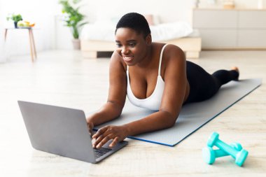 Artı, spor minderinde yatan, dizüstü bilgisayar kullanan, kişisel koçla konuşan ya da evde spor videosu izleyen boyunda bir zenci kadın. Kilolu milenyum bayanı antrenmana ara verdi.